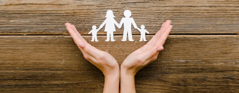 Representacion de unas manos que sostienen una familia hecha de papel