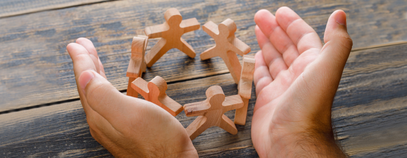 Manos sujetando escultura de madera de personas