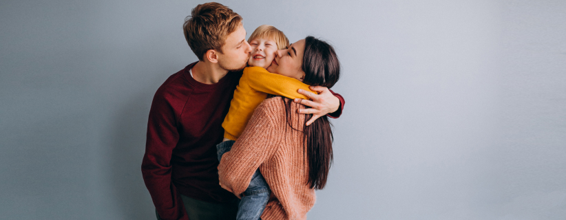 Una familia alzando a un bebé sobre un fondo gris